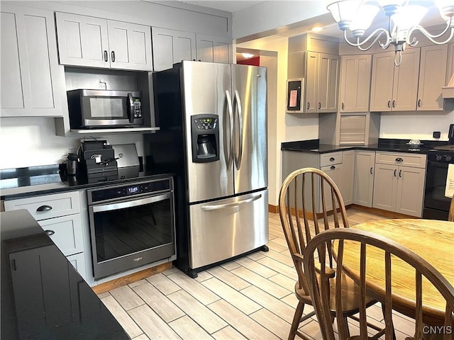 kitchen with an inviting chandelier, dark countertops, light wood finished floors, and stainless steel appliances