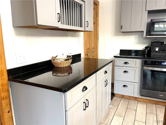 kitchen with stainless steel appliances, light hardwood / wood-style floors, and white cabinets