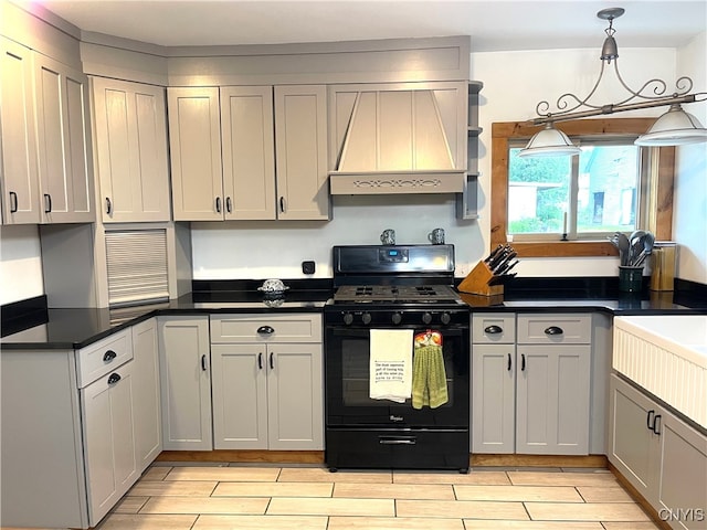 kitchen featuring black range with gas stovetop, gray cabinets, premium range hood, and decorative light fixtures