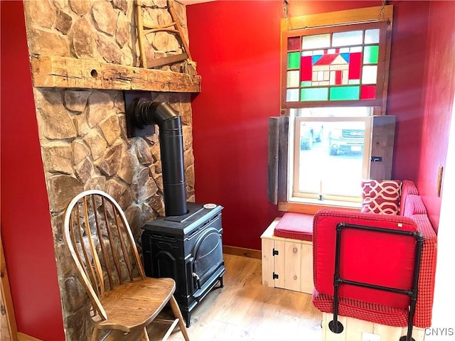 sitting room featuring a wealth of natural light, baseboards, wood finished floors, and a wood stove