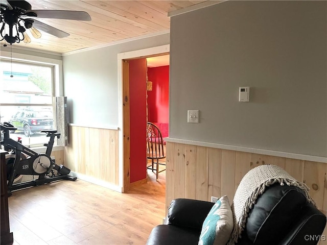 exercise area featuring a wainscoted wall, wood walls, wood ceiling, light wood-type flooring, and a ceiling fan