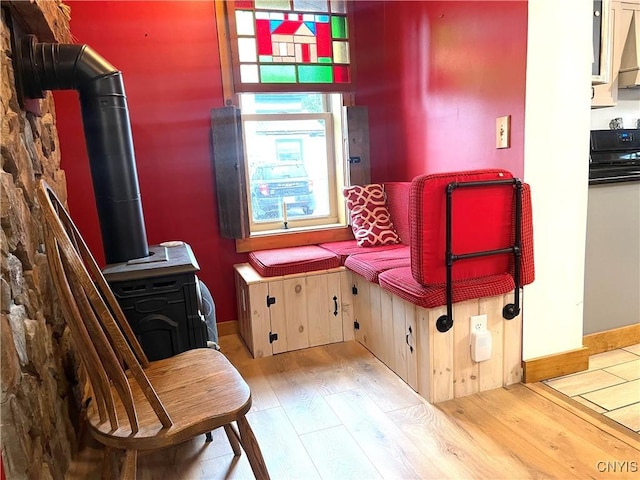 sitting room featuring a wood stove, wood finished floors, and baseboards