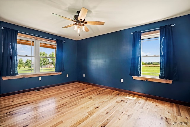 spare room with ceiling fan, a wealth of natural light, and light hardwood / wood-style floors