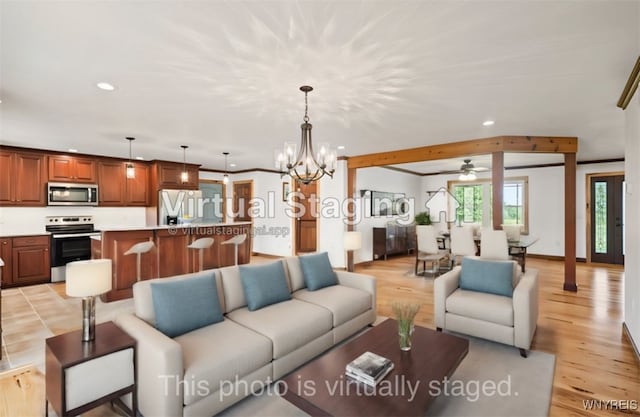 living room featuring ceiling fan with notable chandelier and light hardwood / wood-style floors