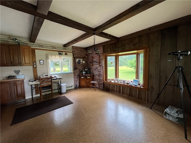 kitchen featuring a baseboard radiator, beamed ceiling, wooden walls, and hanging light fixtures