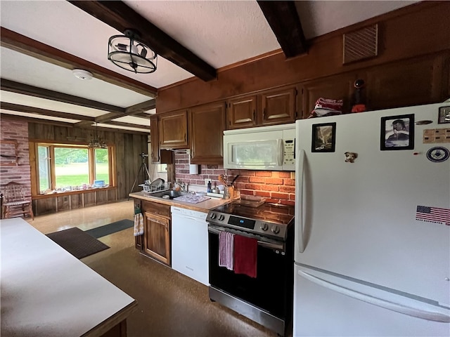 kitchen with white appliances, wood walls, beamed ceiling, decorative light fixtures, and sink