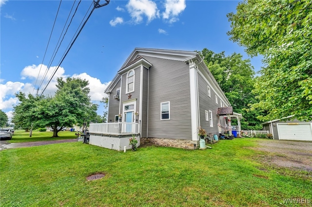 view of side of home with an outdoor structure, a garage, a deck, and a yard