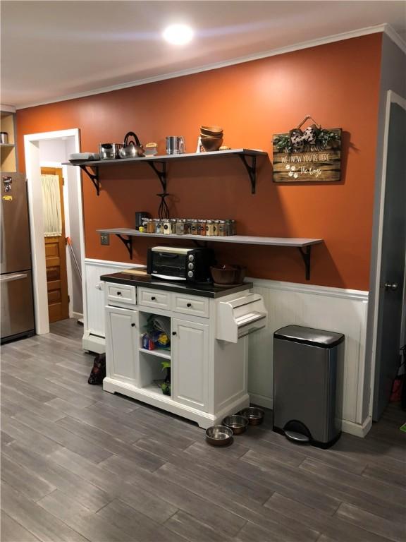 bar featuring dark wood finished floors, crown molding, and freestanding refrigerator