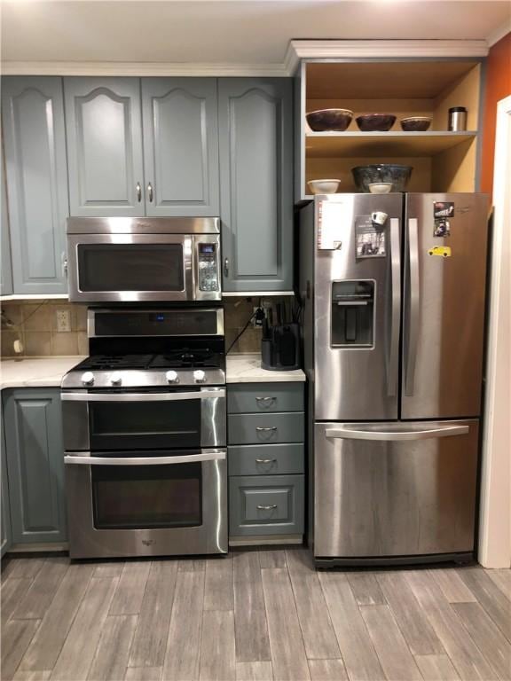 kitchen with stainless steel appliances, decorative backsplash, light countertops, and gray cabinetry