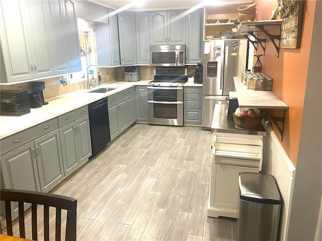 kitchen with stainless steel appliances, gray cabinets, light countertops, wood tiled floor, and a sink