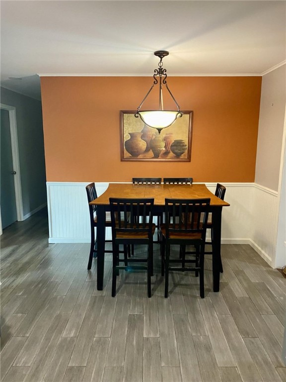 dining space featuring a wainscoted wall, crown molding, and wood finished floors