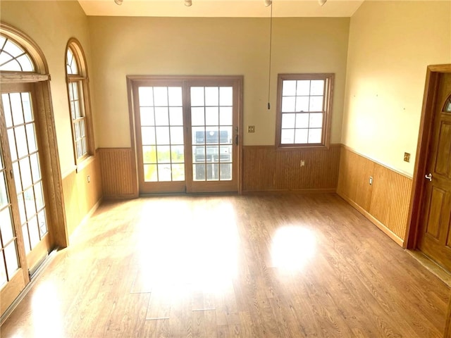 spare room with a wainscoted wall, wood finished floors, and wood walls