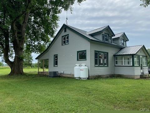 view of side of home featuring central AC and a yard