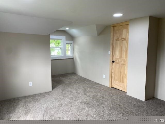 bonus room with carpet flooring and vaulted ceiling