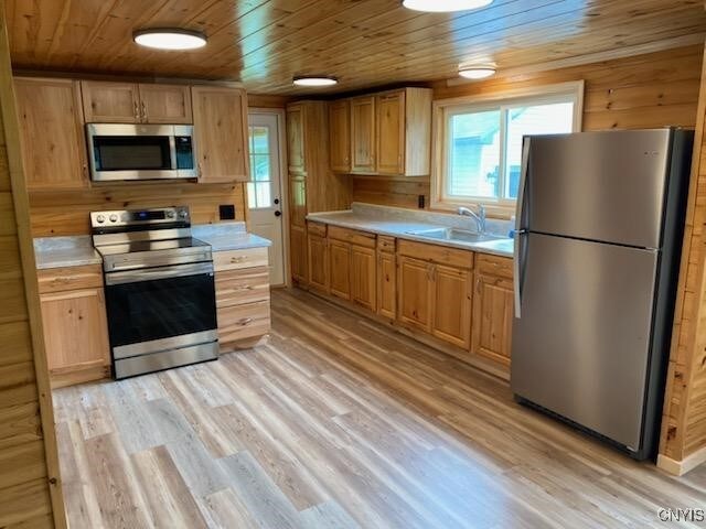 kitchen featuring wood walls, wooden ceiling, sink, light hardwood / wood-style floors, and appliances with stainless steel finishes