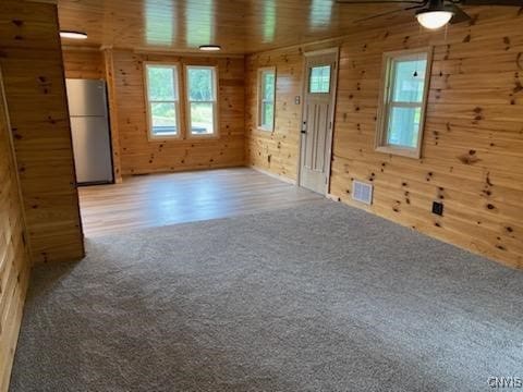 spare room with ceiling fan, carpet floors, and wood walls