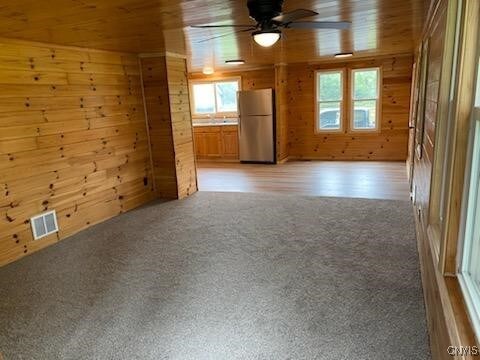 interior space with wooden ceiling, ceiling fan, and wooden walls