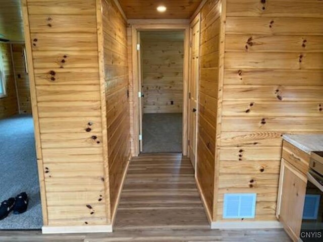 corridor with hardwood / wood-style flooring and wooden walls