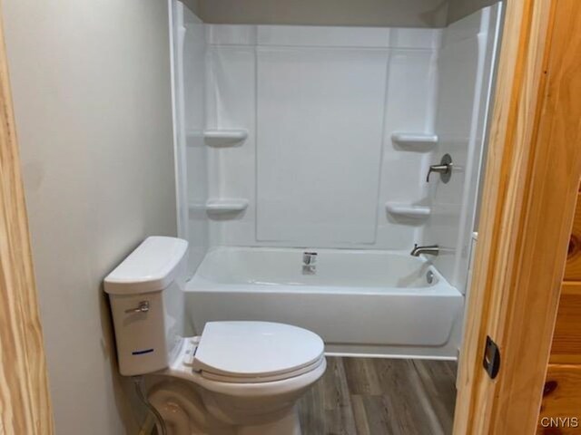 bathroom with toilet, hardwood / wood-style flooring, and bathtub / shower combination