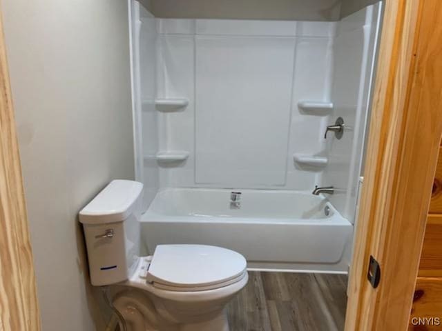 bathroom featuring hardwood / wood-style flooring,  shower combination, and toilet