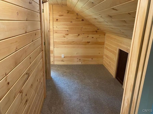 additional living space featuring lofted ceiling, wooden ceiling, dark colored carpet, and wood walls