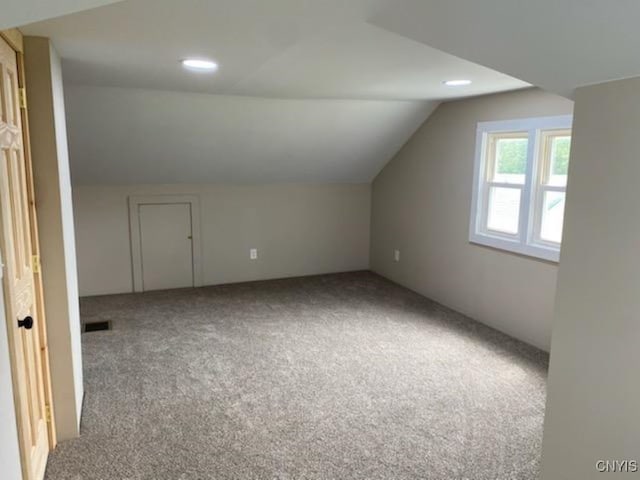 bonus room featuring vaulted ceiling and light colored carpet