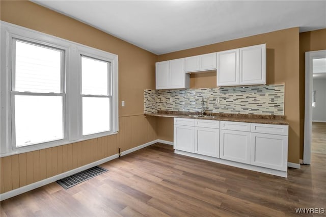 kitchen featuring visible vents, dark wood-type flooring, a sink, white cabinetry, and wainscoting