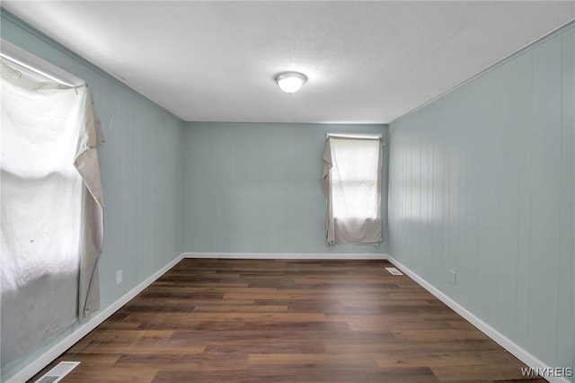 empty room featuring visible vents, baseboards, and wood finished floors