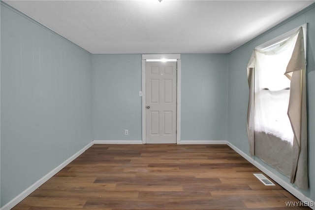 spare room featuring visible vents, baseboards, and wood finished floors