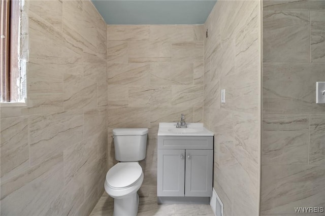 bathroom with vanity, tile walls, and toilet