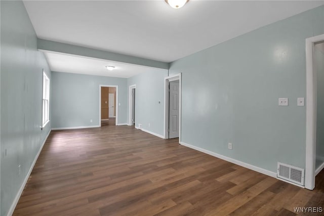 unfurnished room featuring dark wood finished floors, visible vents, and baseboards