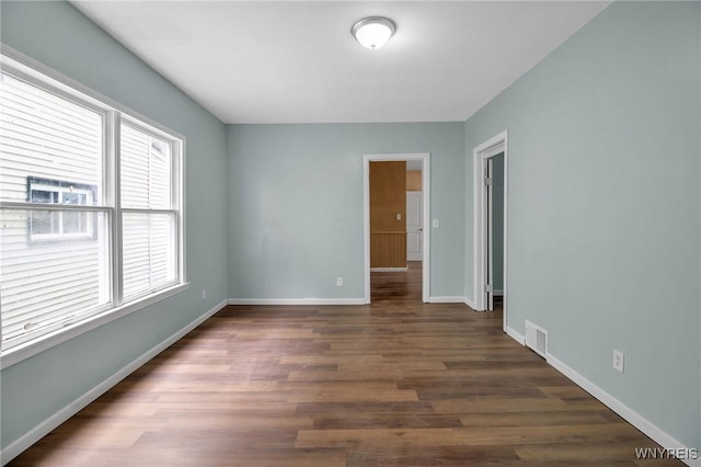 unfurnished room with wood finished floors, visible vents, and baseboards