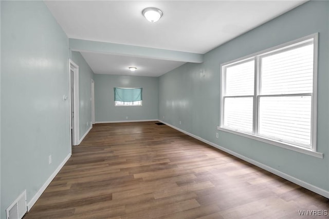 unfurnished room with visible vents, plenty of natural light, baseboards, and wood finished floors