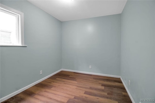 spare room with baseboards and wood finished floors