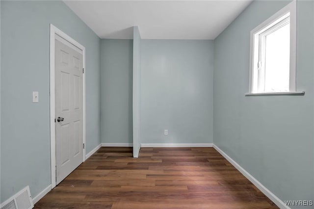 spare room featuring visible vents, baseboards, and dark wood-style floors