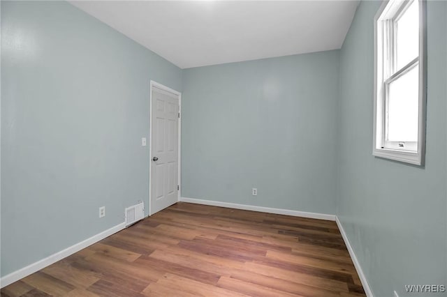 unfurnished room featuring visible vents, baseboards, and wood finished floors