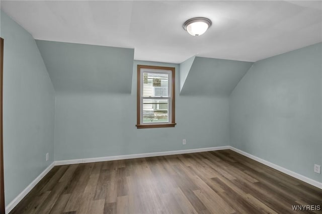 additional living space with dark wood finished floors, lofted ceiling, and baseboards