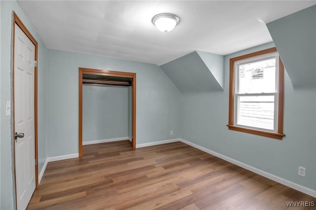 additional living space featuring baseboards, lofted ceiling, and wood finished floors