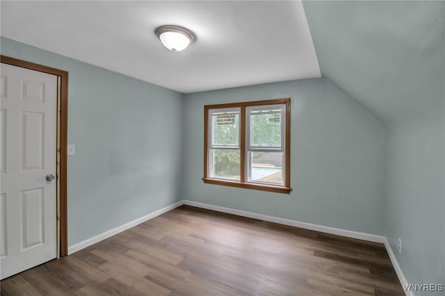 bonus room featuring dark wood-type flooring, baseboards, and vaulted ceiling