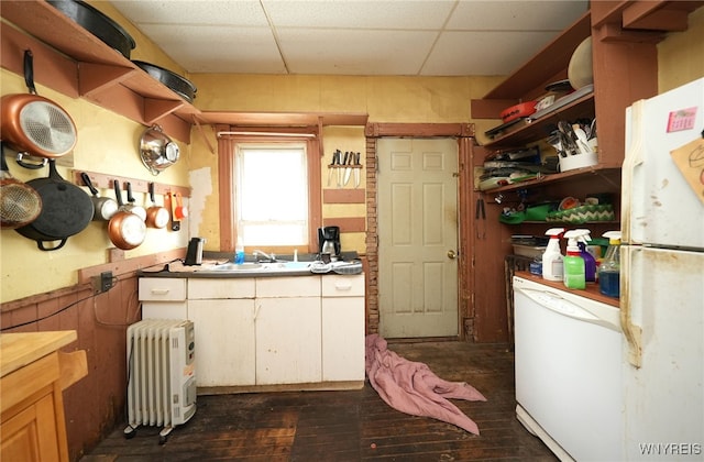 kitchen with sink, a paneled ceiling, white appliances, dark hardwood / wood-style flooring, and radiator heating unit