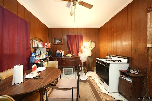 kitchen with wood walls, white range with gas cooktop, ceiling fan, and ornamental molding