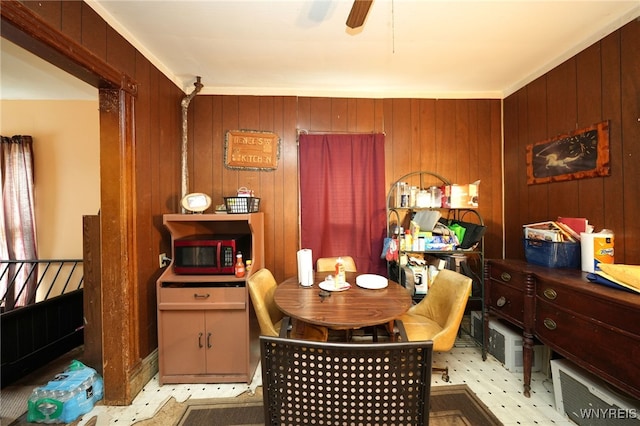 dining room with ceiling fan and wooden walls