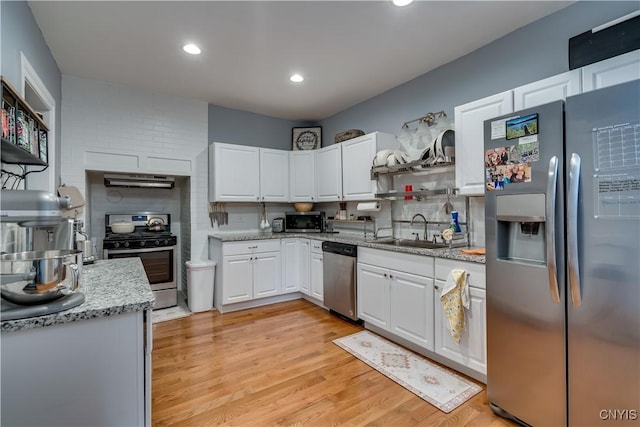 kitchen with sink, white cabinetry, light hardwood / wood-style flooring, stainless steel appliances, and light stone countertops