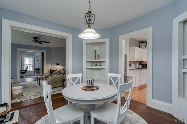 dining room featuring dark wood-type flooring, built in features, and ceiling fan