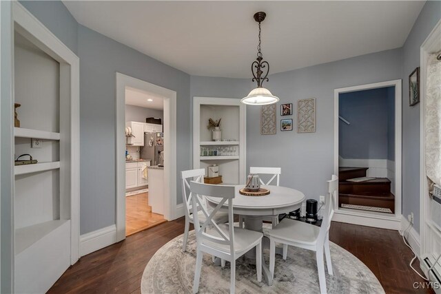 dining area featuring built in shelves and dark hardwood / wood-style flooring