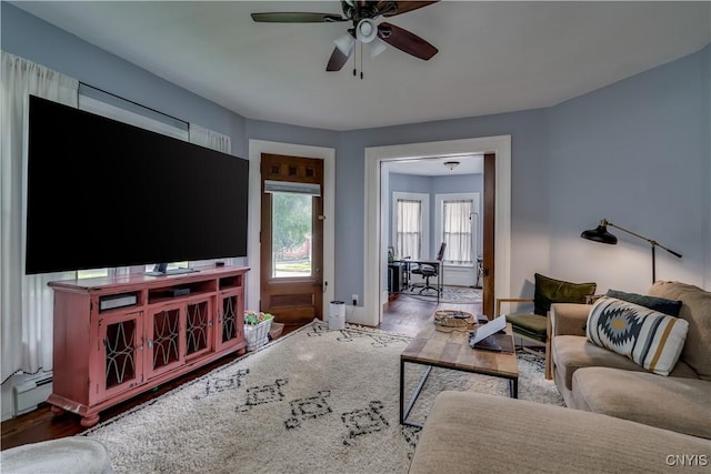 living room with hardwood / wood-style flooring, ceiling fan, and baseboard heating