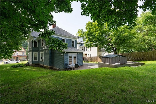 back of property featuring a storage unit and a lawn