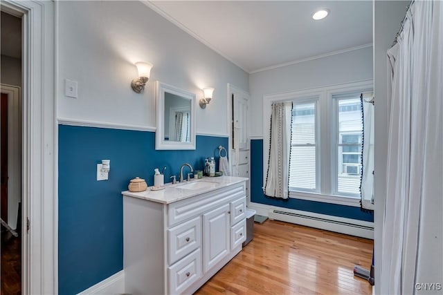 bathroom featuring vanity, a baseboard heating unit, ornamental molding, and hardwood / wood-style floors