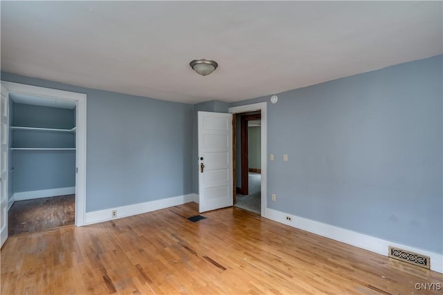 unfurnished bedroom featuring a spacious closet, light wood-type flooring, and a closet