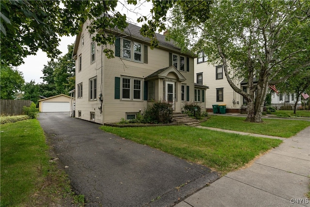 colonial-style house with a garage, an outdoor structure, and a front yard